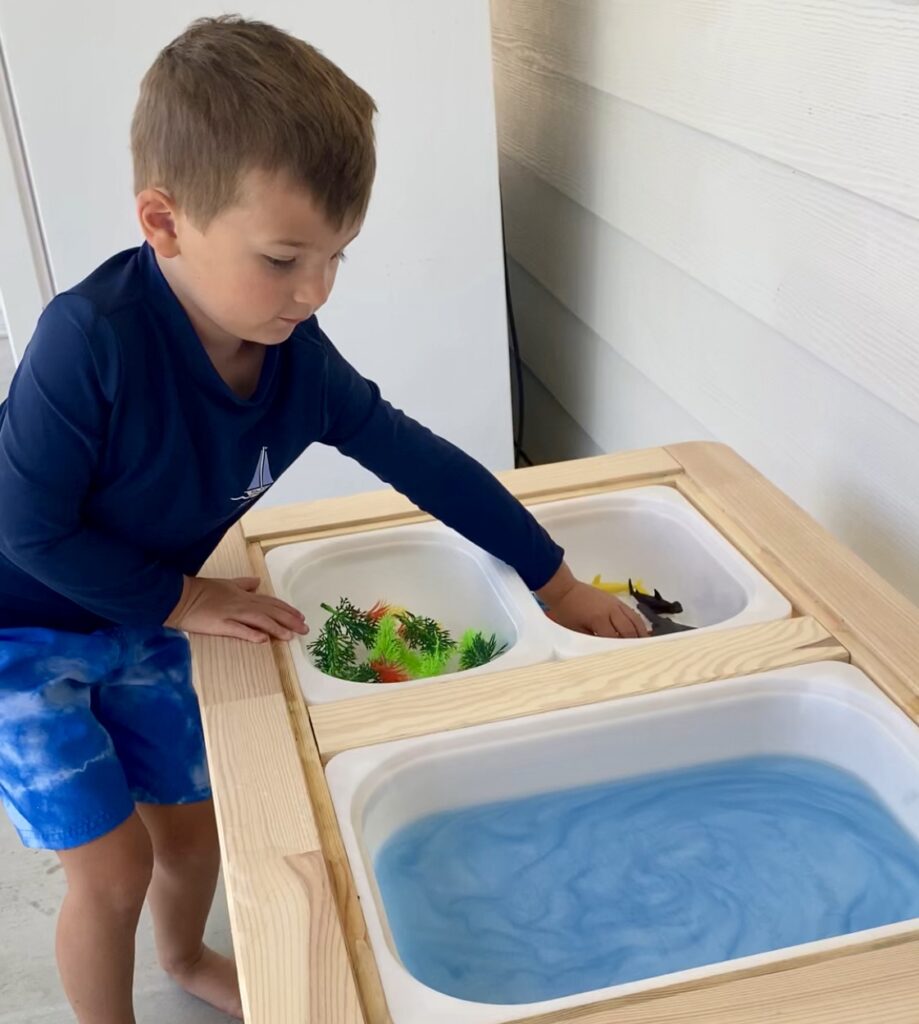 child playing with water table sensory ocean themed with shimmery water